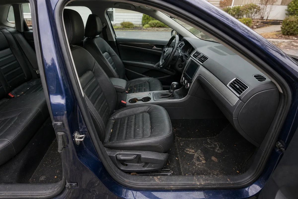 Dark navy sedan interior with crumbs and muddy floor mats before detailing